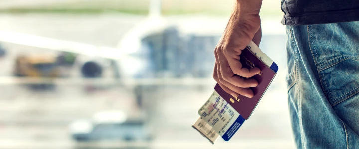 Schmuckgrafik Fachkräfteeinwanderung männliche Hand mit Boardingpass und Reisepass vor Flugzeug