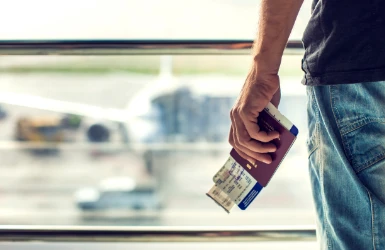 Schmuckgrafik Fachkräfteeinwanderung männliche Hand mit Boardingpass und Reisepass vor Flugzeug