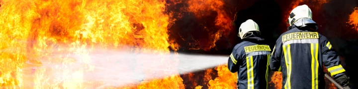 Zwei Feuerwehrmänner löschen ein Feuer