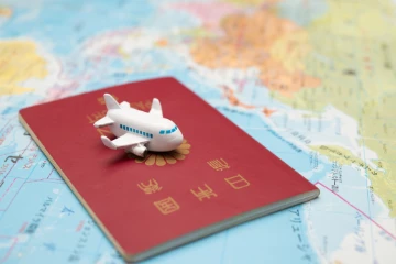Japanischer Pass und Spielzeugflugzeug auf einer Landkarte