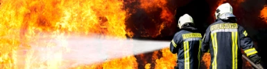 Zwei Feuerwehrmänner löschen ein Feuer