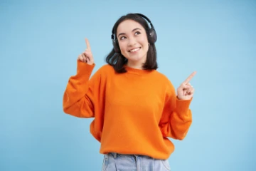 Junge fröhliche Frau hört etwas auf Wireless Kopfhörern an