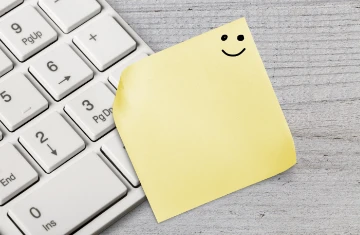 Notizzettel mit Smiley auf Tastatur