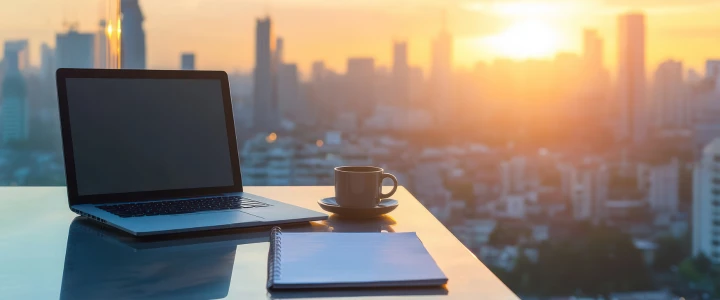 Laptop auf Glastisch mit Blick auf die städtische Skyline von einer Hochhauswohnung aus