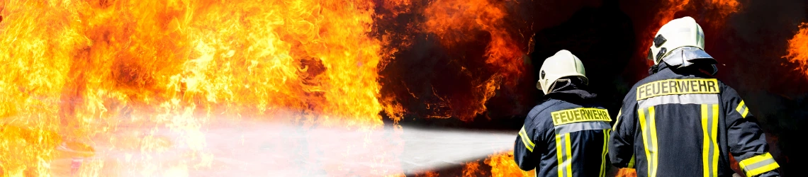 Zwei Feuerwehrmänner löschen ein Feuer