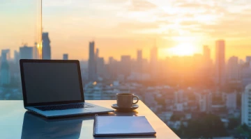Laptop auf Glastisch mit Blick auf die städtische Skyline von einer Hochhauswohnung aus