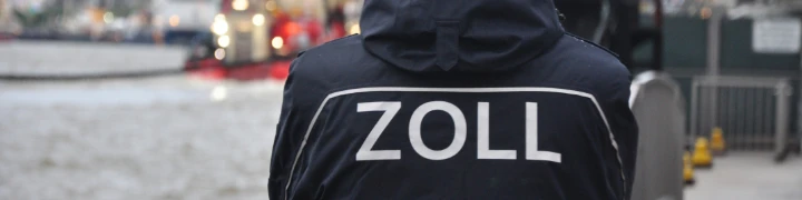 Ein Zollbeamter von hinten fotografiert schaut auf den Hafen