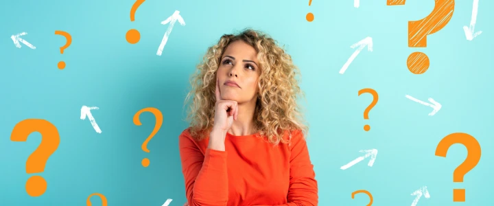 Junge Frau steht vor einer Wand mit vielen Fragezeichen