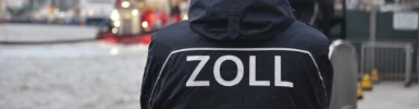 Ein Zollbeamter von hinten fotografiert schaut auf den Hafen