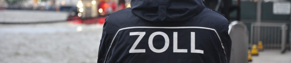 Ein Zollbeamter von hinten fotografiert schaut auf den Hafen