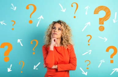 Junge Frau steht vor einer Wand mit vielen Fragezeichen