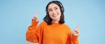 Junge fröhliche Frau hört etwas auf Wireless Kopfhörern an