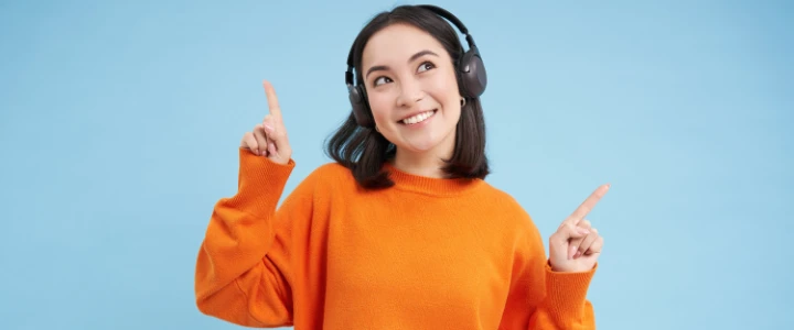 Junge fröhliche Frau hört etwas auf Wireless Kopfhörern an